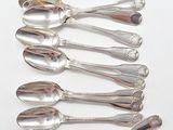 six silver spoons are lined up in a row on a white surface