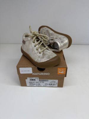 une paire de chaussures pour bébé dans une boîte posée sur une surface blanche