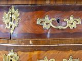 a wooden chest of drawers with gold decorations on it