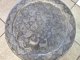 une assiette en argent ornée d'un motif, posée sur un sol carrelé