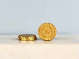 two gold coins sitting on top of a marble slab