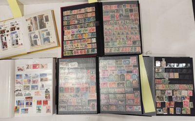 beaucoup de timbres posés sur une table, à côté d'un classeur