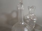 two glass vases sitting on a table next to a mirror