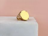 a close up of a gold signet ring on a marble block