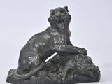 a statue of a dog on a rock with a bird in its mouth