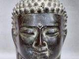 statue représentant une tête de Bouddha aux yeux fermés sur fond blanc