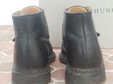 pair of black leather boots on a tile floor with a white box in the background