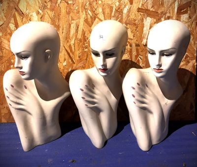 trois têtes de mannequins posées sur une table bleue