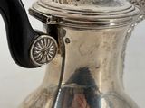 a silver tea pot with a black handle on a table
