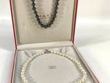 un collier de perles blanches dans un coffret rouge sur fond blanc