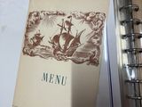 a menu in a book on a table next to a cup of coffee