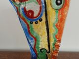 a colorful vase on a wooden table with a white wall in the background