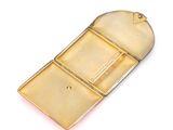 a small gold case with a key on a white surface