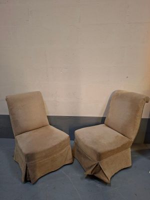 pair of beige slipper chairs sitting in a corner of a room