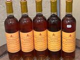 six bottles of wine sitting on top of a wooden barrel