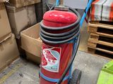 un extincteur rouge posé sur un chariot dans un entrepôt