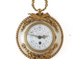 une horloge en or accrochée au mur, entourée d'une corde