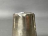 a silver thimble sitting on a gray surface
