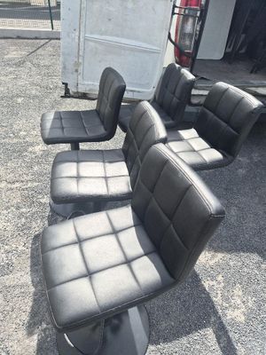 quatre fauteuils en cuir noir posés sur un parking, à côté d'un camion