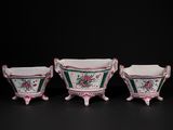 three pink and green vases sitting on top of a black surface