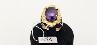 un gros plan d'une bague sertie d'une pierre violette, posée sur un socle