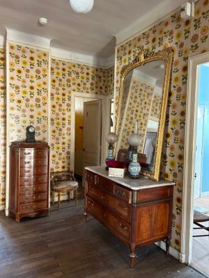 une commode et un miroir dans une pièce où des tournesols ornent les murs