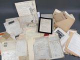 une pile de vieux papiers posée sur une table où se trouve un cadre photo