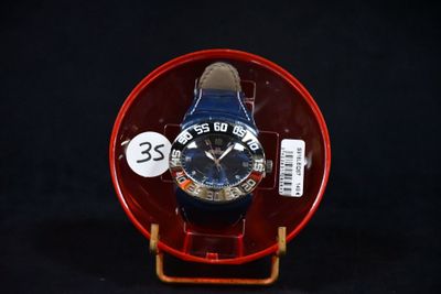 une montre bleue posée sur une assiette rouge, sur un fond noir