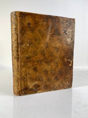 un vieux livre posé sur une table blanche à côté d'un mur blanc