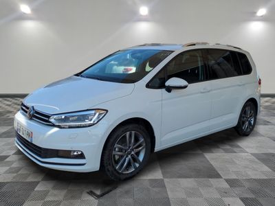 Une Volkswagen Touran blanche est garée dans une grande pièce