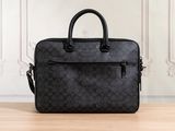 a black coach laptop bag sitting on top of a wooden table
