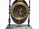a black and gold clock on a stand on a white background
