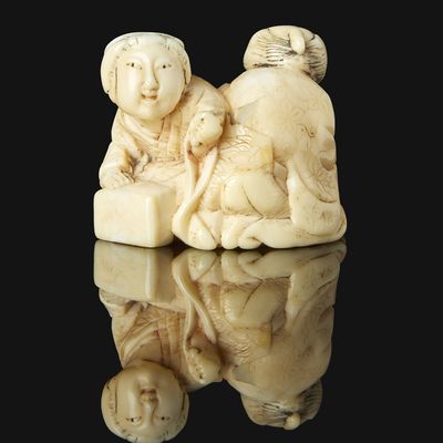 two ivory figurines of a woman and a child on a black surface