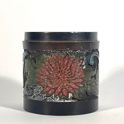 un récipient noir orné d'une fleur rouge