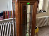 une armoire en bois avec une porte vitrée, dans un coin de la pièce