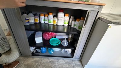 une personne debout devant une armoire remplie de flacons de médicaments