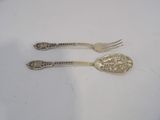 two forks and a spoon sitting on a white table