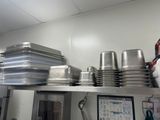 de nombreuses casseroles et poêles rangées sur une étagère dans une cuisine