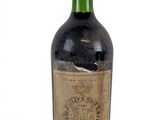 une vieille bouteille de vin posée sur une surface blanche