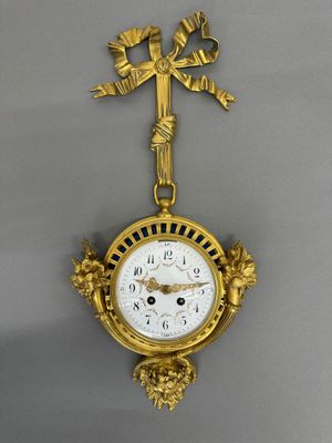 a gold clock hanging on the wall with a cross on it