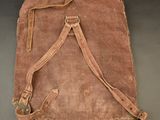 an old brown canvas bag with a leather strap on a black surface