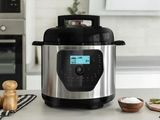 an electric pressure cooker sitting on top of a counter next to a bowl of food