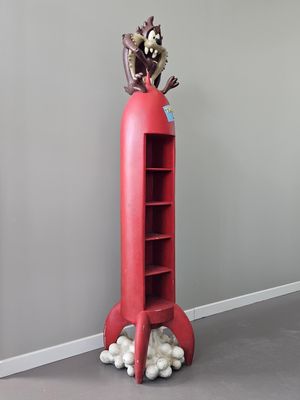 une grande bibliothèque rouge sur laquelle est posé un animal en peluche