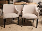pair of upholstered chairs sitting in front of a painting on a wall