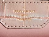 a close up of a pink purse with a gold logo on it