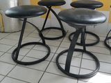 three black stools sitting on top of a tiled floor next to a window