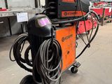 an orange and black welding machine in a warehouse with other equipment