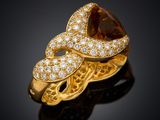 a yellow gold ring with diamonds and a pear shaped stone