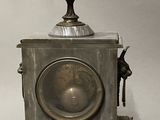 a silver clock with a bird on top of it