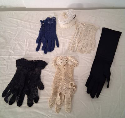 quatre paires de gants et un bonnet sont disposés sur un lit